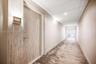 Wood-finish door with brushed metal hardware, recessed ceiling lighting, and wall-mounted unit signage