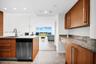 Kitchen featuring flat-panel wood-finish cabinetry, stone countertops, stainless steel dishwasher, undermount sink with arched faucet, and recessed li
