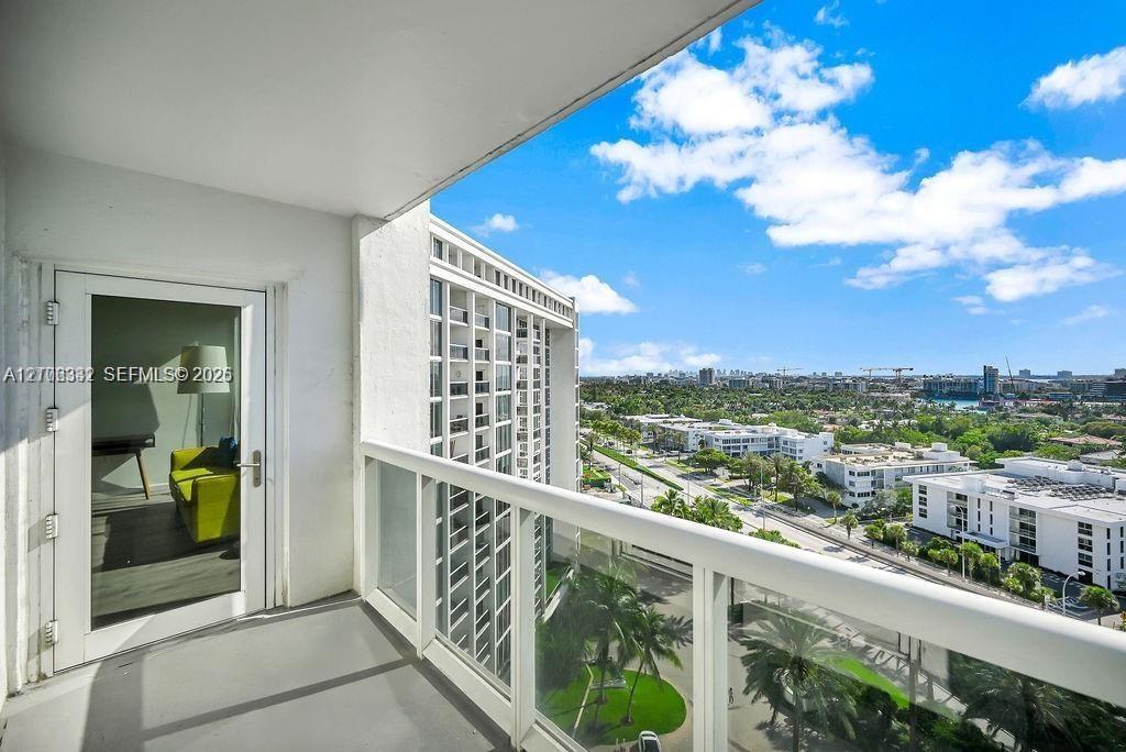 Private balcony featuring white metal railings, glass panel inserts, and a concrete floor