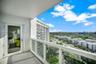 Private balcony featuring white metal railings, glass panel inserts, and a concrete floor