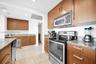 Kitchen featuring wood cabinetry, stone countertops, stainless steel appliances, and tile flooring
