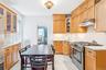 Kitchen with stainless steel range with gas cooktop, under cabinet range hood, radiator heating unit, tasteful backsplash, and light stone countertops