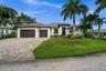 Mature tropical landscaping and tile roof make for a grand entry
