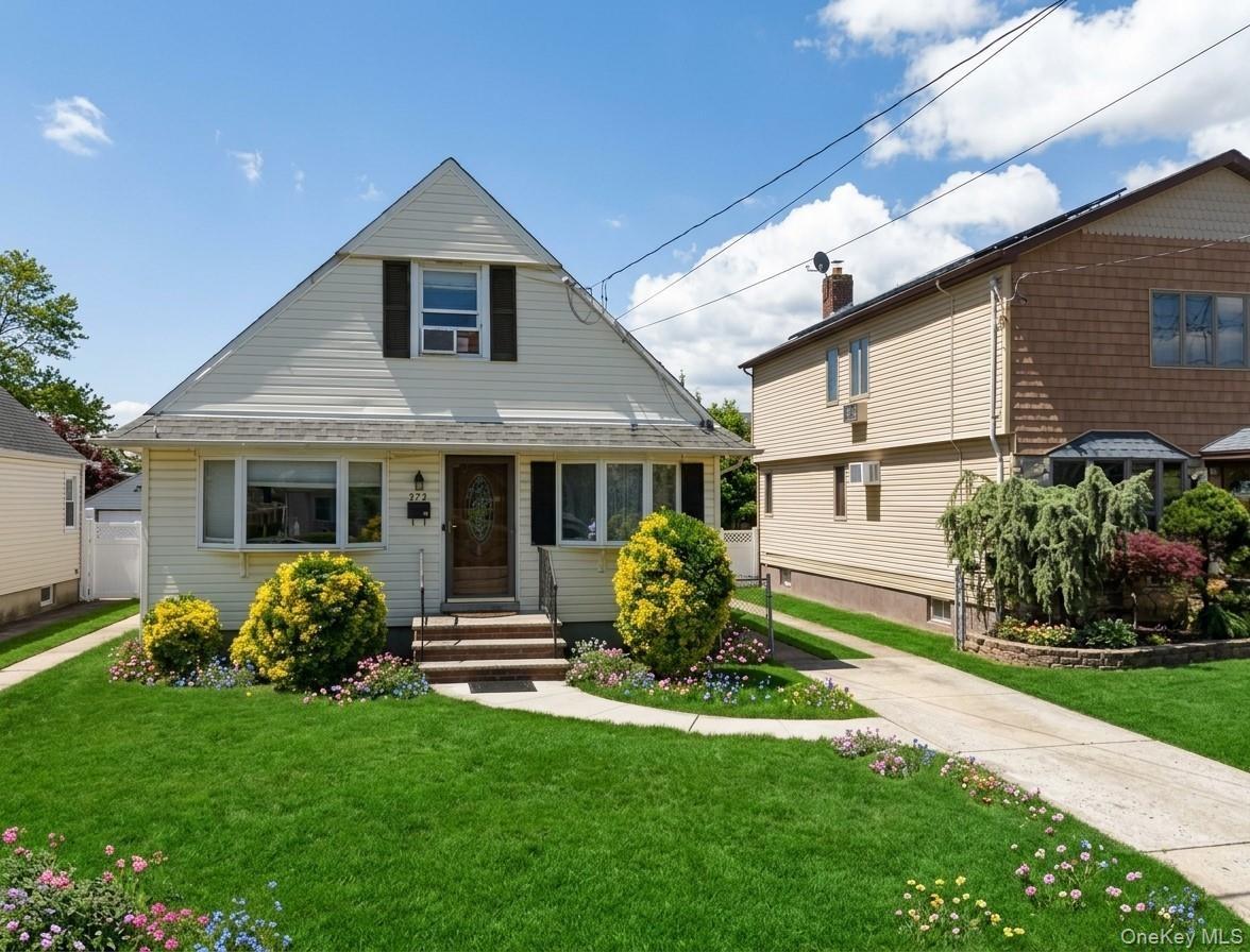 Gable-roof exterior featuring light-toned horizontal siding, arched entryway, multi-pane front windows, and a paved private driveway
