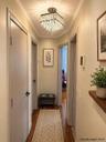 Hallway featuring wood-finish flooring, a tiered crystal flush-mount light fixture, and crown molding