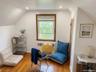 Sloped ceiling architecture featuring wood-finish flooring, a centrally positioned window with wood trim, and recessed lighting