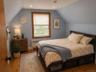 Bedroom featuring wood-finish flooring, sloped ceilings, and a window framed by wood trim