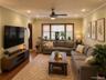 Living area featuring wood-finish flooring, recessed lighting, crown molding, and a multi-panel window configuration with dark wood trim