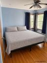 Wood-finish flooring, dual windows with wood trim, and a ceiling fan with integrated lighting