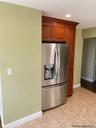 Stainless steel refrigerator with bottom-mount freezer, integrated into built-in wood-finish cabinetry with crown molding and recessed lighting