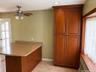 Custom wood-finish floor-to-ceiling cabinetry, stone-texture countertop, wood-finish breakfast bar, and brushed-metal ceiling fan with integrated ligh