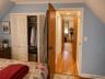 Wood-finish flooring, white louvered-door closet with built-in shelving, solid wood interior doors, and crown molding