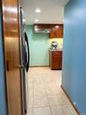 Kitchen featuring wood cabinetry, stainless steel range hood, ceramic tile flooring, and recessed ceiling lighting