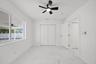Large-format tile flooring, dual-panel closet doors, matte black ceiling fan with integrated lighting, and white interior doors