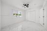 Interior space featuring large-format tile flooring with a neutral veined pattern, dual-panel closet doors, and a matte black ceiling fan with an inte