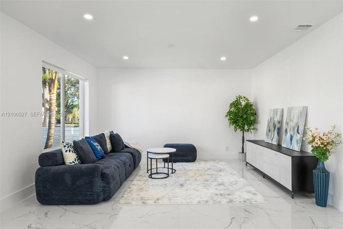 Neutral-toned interior featuring large-format tile flooring, recessed lighting, and a wide sliding glass door