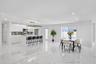 Kitchen featuring white high-gloss cabinetry, stone-finish countertops, stainless steel appliances, a center island with a multi-light pendant fixture