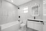 Modern bathroom featuring floor-to-ceiling large-format tile, a floating vanity with a vessel sink, a matte black faucet and shower head, and a built-