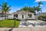 Single-story residence featuring a smooth stucco exterior, a recessed entryway with a decorative arch, a concrete driveway, and white vinyl privacy fe