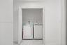 Laundry alcove featuring white bi-fold doors, white interior walls, and tile flooring