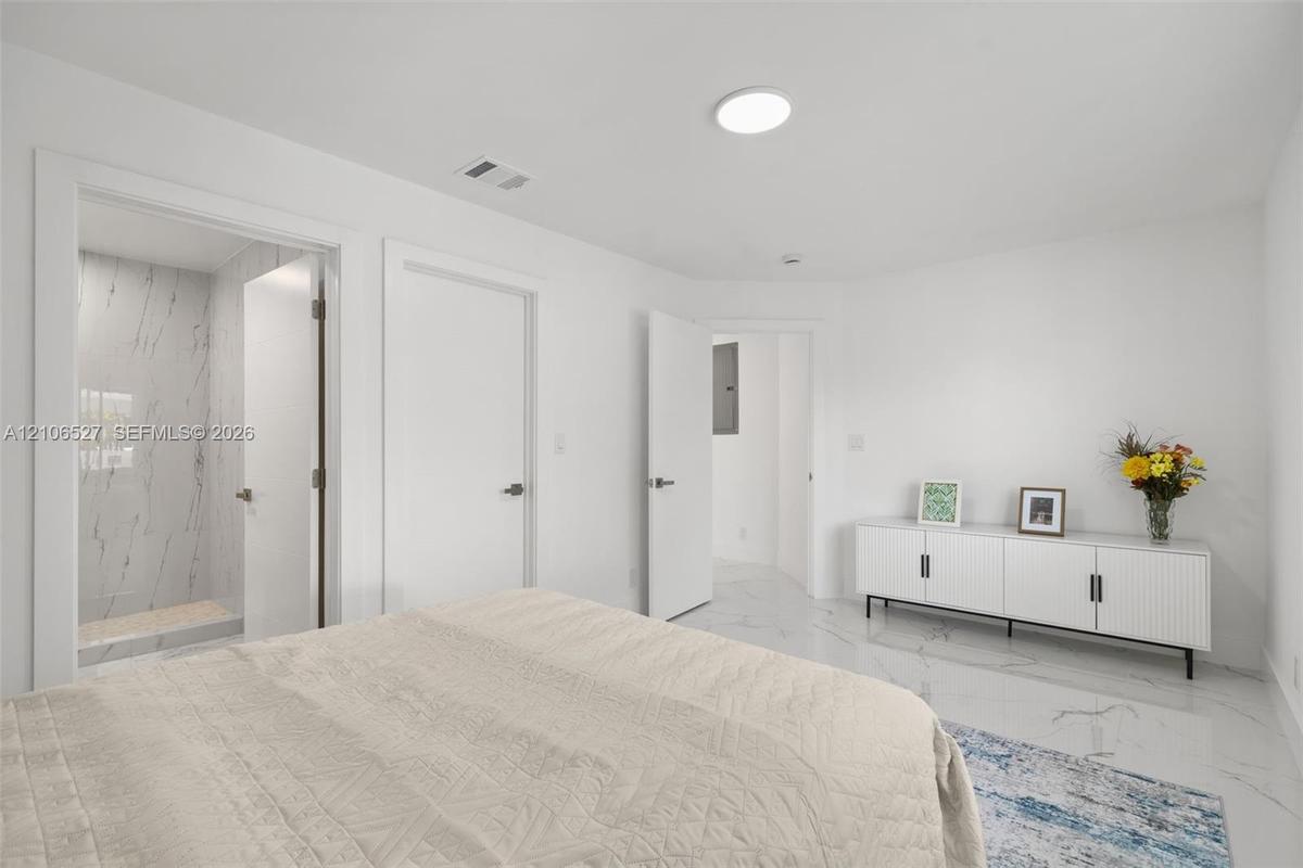 Room featuring white-finish tile flooring with gray veining, flush-mount lighting, and an enclosed shower stall with floor-to-ceiling veined tile wall