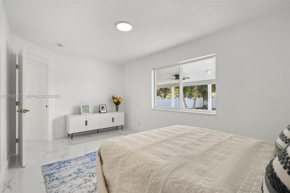 Room featuring polished, white, veined-finish flooring, neutral walls, a single-panel interior door, and a large horizontal window