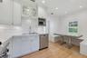 Kitchen featuring white shaker-style cabinetry, subway tile backsplash, stone-finish countertops, stainless steel appliances, and integrated bench sea