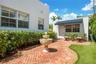Courtyard featuring a herringbone-pattern brick patio, a central tiered stone fountain, exterior building structures with textured white stucco siding