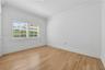 Interior space featuring wood-finish flooring, crisp white walls, crown molding, and plantation shutters
