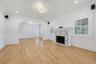Living area featuring wood-finish flooring, a decorative tile-surround fireplace, arched architectural entryways, crown molding, and plantation shutte