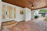 Covered entryway featuring a wood-plank ceiling, herringbone brick paving, and a glass-paneled entry door with sidelights