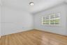 Interior space featuring wood-finish flooring, white walls, crown molding, a flush-mount ceiling light, and windows equipped with plantation shutters