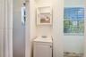 White vanity with an integrated basin, chrome-finished dual-handle faucet, white framed medicine cabinet, and a shower area featuring white wall tile