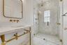 Console-style vanity with a stone countertop and brass-finish plumbing fixtures, glass-enclosed walk-in shower featuring herringbone tile pattern, and