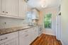 Kitchen featuring white shaker-style cabinetry, stone-patterned countertops, white subway tile backsplash, wood-finish flooring, and a flush-mount cei