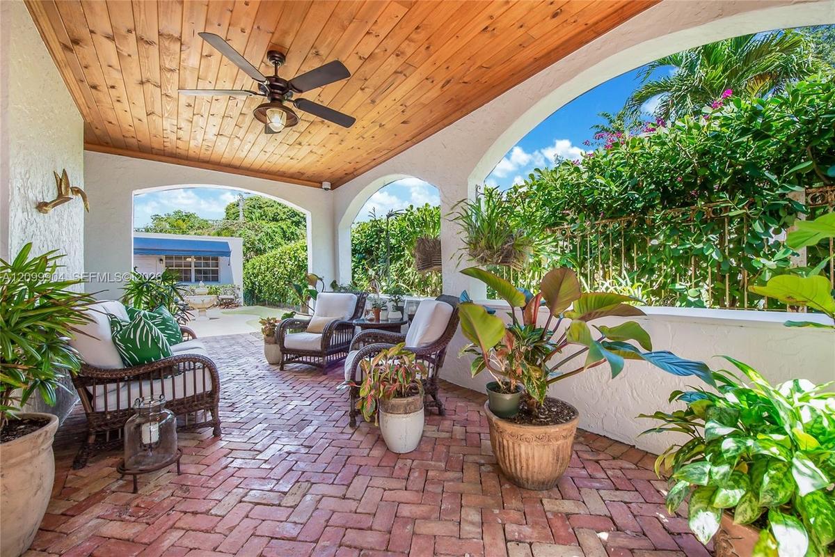 Covered lanai featuring a tongue-and-groove wood ceiling, brick flooring in a herringbone pattern, integrated ceiling fan, and structural archways