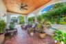 Covered lanai featuring a tongue-and-groove wood ceiling, brick flooring in a herringbone pattern, integrated ceiling fan, and structural archways
