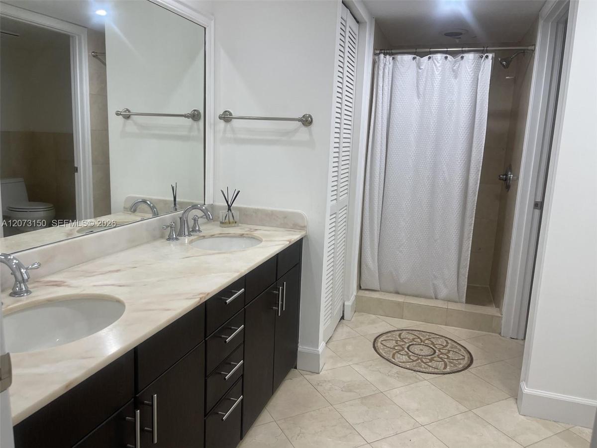 Kitchen featuring flat-panel cabinetry, stone countertops with a matching full-height backsplash, wood-finish flooring, and stainless steel appliances