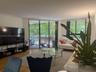 Living area featuring wood-finish flooring and a kitchen pass-through counter with stone-finish surfaces and white cabinetry