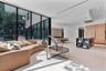 Floor-to-ceiling glass walls, integrated light-toned cabinetry, a modern kitchen island with built-in shelving, recessed ceiling lighting, and large-f