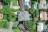Aerial perspective featuring a hip-roof structure, rectangular swimming pool, paved driveway, and mature landscaping