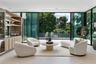 Floor-to-ceiling retractable glass walls, built-in recessed ceiling lighting, light-toned large-format tile flooring, and custom wood-paneled cabinetr