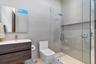 Floating vanity with wood-finish cabinetry, rectangular vessel sink, wall-to-wall mirror, glass-enclosed shower with rainfall showerhead, and wall-mou