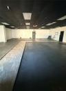 Open interior space featuring a matte black drop ceiling with recessed lighting, smooth white walls, concrete flooring, and tiled floor inlays
