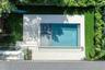 Modern residence featuring a clean-lined architectural facade with expansive glass panels, rendered white exterior walls, and manicured green lawn bor