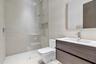 Floating vanity with wood-finish cabinetry, white countertop, integrated sink, rainfall shower head, and full-height glass shower panel