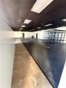 Open floor plan featuring a combination of tile flooring and dark-finished concrete flooring, dark drop ceiling with recessed lighting, and built-in m