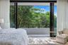 Floor-to-ceiling retractable glass wall opening to a private balcony with horizontal cable railing and concrete masonry wall