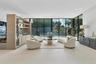 Open-concept living area featuring floor-to-ceiling glass walls, large-format tile flooring, recessed ceiling lighting, and a custom built-in wood-fin