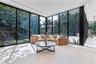 Floor-to-ceiling glass wall panels with black framing, large-format tile flooring, and recessed ceiling lighting